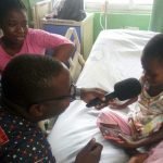 Morning Starr host Francis Abban presenting chocolate to one of the kids at the centre