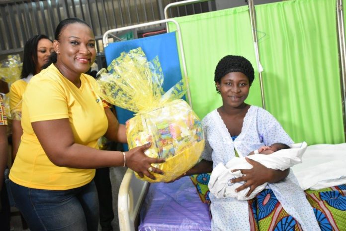 Mrs Jemima Kotei Walsh, Customer Relations Executive of MTN Ghana presenting hamper to a mother