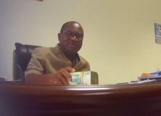 Robert Sarfo-Mensah in the act of taking the cash in his office