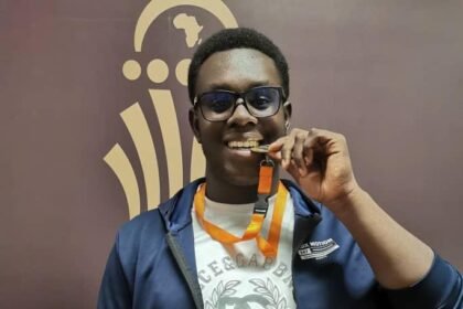 AIS student Kweku Ayim holding gold medal after winning discus event for Ghana