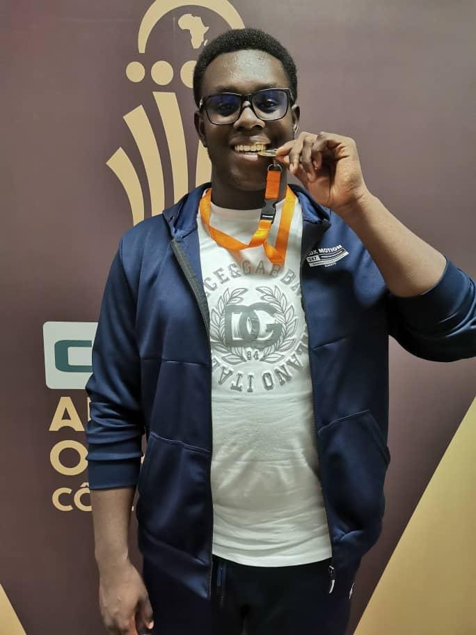 AIS student Kweku Ayim holding gold medal after winning discus event for Ghana