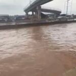 Flooded street near Ofankor Barrier in Accra with submerged vehicles and stranded commuters